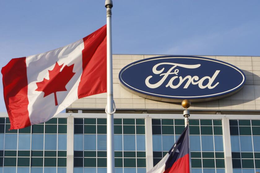 A Canadian flag flutters in the wind near a Ford logo on the automaker's headquarters, Oct. 26, 2009 in Dearborn, Mich. Canadian autoworkers ratified a new labor agreement with Ford Motor Co. on Sunday, Sept. 24, 2023 averting a threatened strike and potentially setting a precedent that could play out in the United Auto Workers strike at automaker facilities in the U.S. (AP Photo/Carlos Osorio)
