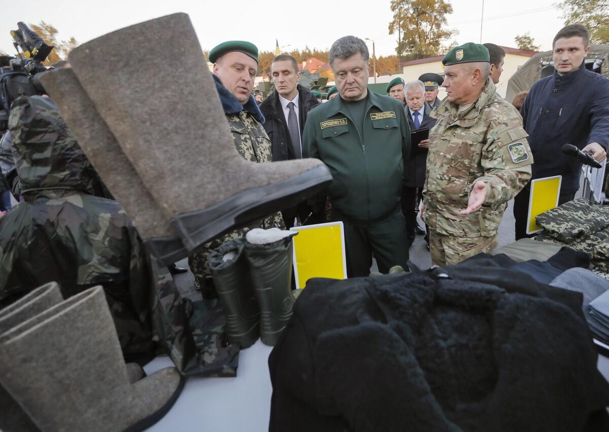 Ukrainian President Petro Poroshenko, center, inspects winter gear and ammunition for a border guard unit near Kiev on Tuesday. A Sept. 5 cease-fire has all but collapsed as fighting intensifies over strategic venues in eastern Ukraine.