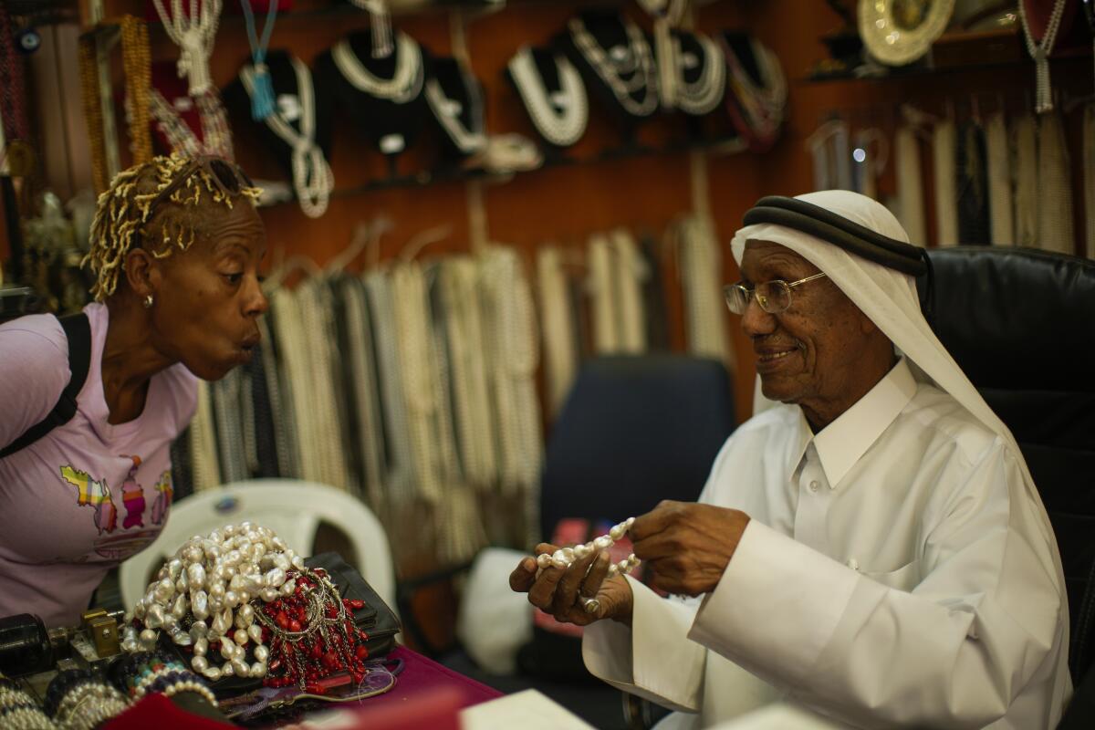 A former pearl diver talks to a client in his pearl shop.