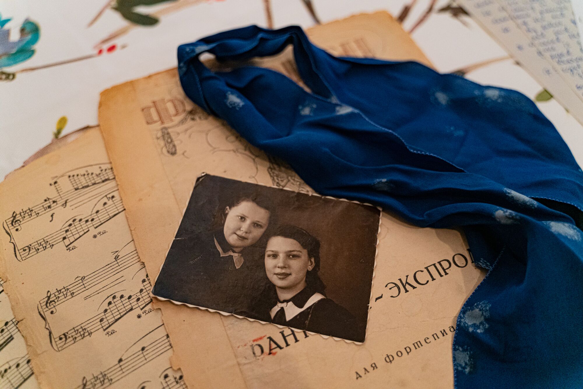 A photo of two girls atop a sheet of Chopin music and a blue scarf.