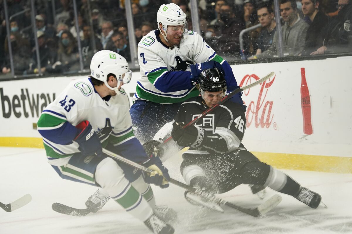 Kings' Blake Lizotte loses his balance as he goes after the puck against Vancouver Canucks' Quinn Hughes and Luke Schenn.
