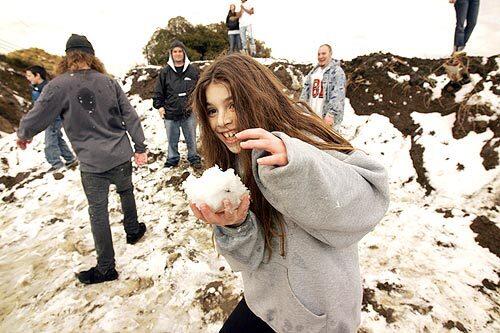 Sarah Rosenberg runs with a snowball during a snow attack on a friend as people stopped to play in the snow between tunnel 2 and tunnel 3 along Kanan Dume Road in the hills above Malibu.