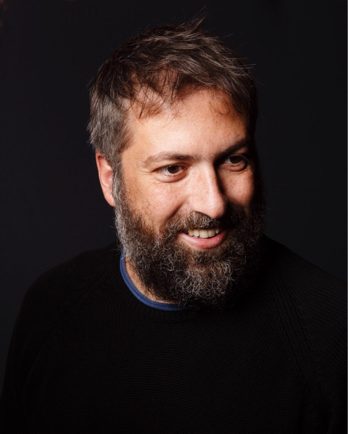 A smiling man with a beard and mustache.