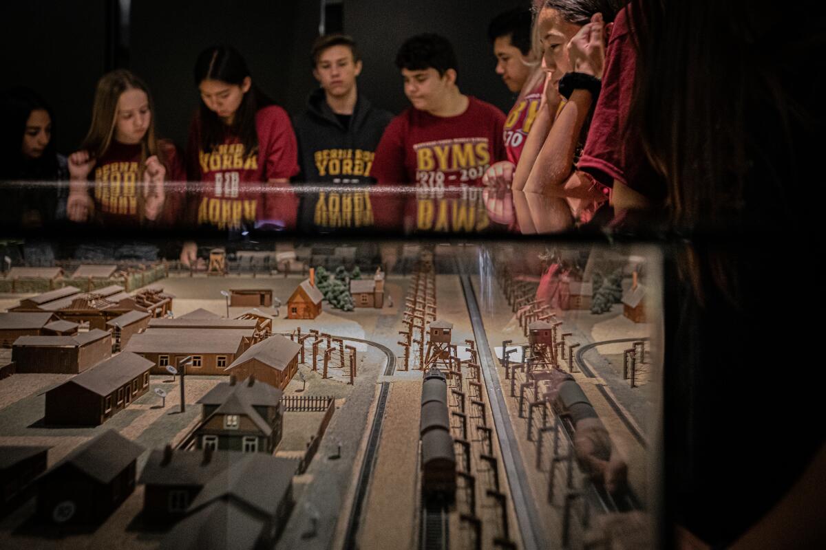Young visitors to a museum examine a model of a Nazi death camp.