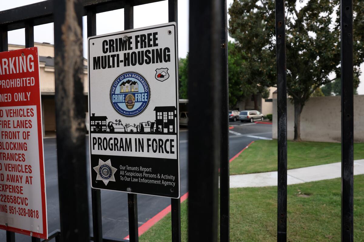 A sign on an apartment complex gate reads "CRIME FREE MULTI-HOUSING PROGRAM IN FORCE."
