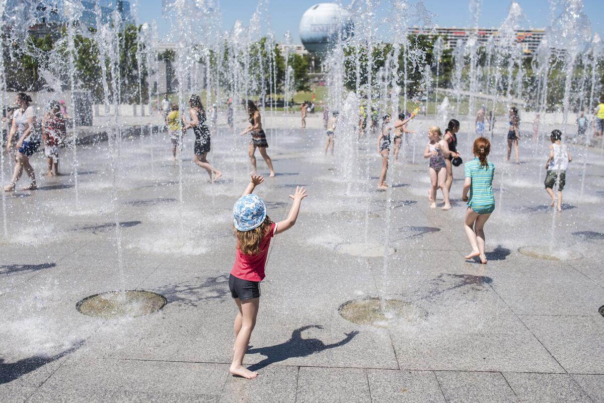 Niños juegan en las fuentes de la plaza André Citroen en París, 30 de junio de 2015. Una masa de aire caliente desde Africa provoca temperaturas inusualmente altas en Europa. (AP Photo/Kamil Zihnioglu)