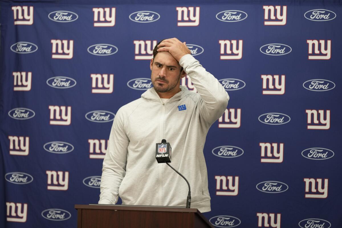 Giants quarterback Daniel Jones holds his head during a news conference.