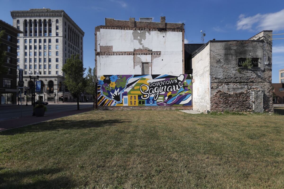 Buildings from different eras of the city's history surround an empty lot in downtown Saginaw, Mich., Monday, June 29, 2020. President Donald Trump won Saginaw county by just over 1,000 votes in 2016, capitalizing on the rusting industrial city's frustrations and its dislike of Democrat Hillary Clinton. (AP Photo/Charles Rex Arbogast)