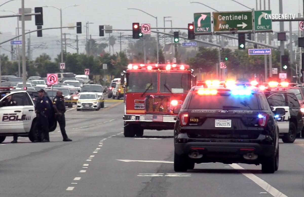 A firetruck and police vehicles with flashing lights block an intersection.