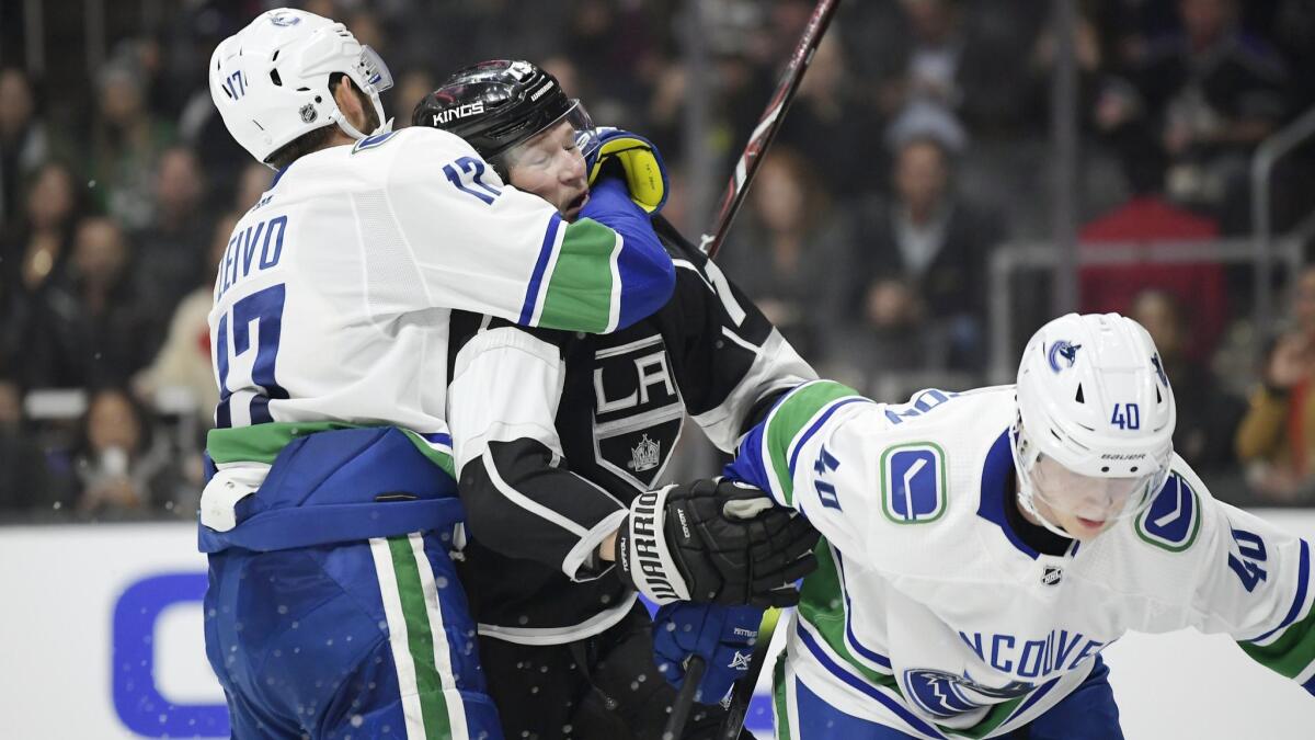 Kings right wing Tyler Toffoli, center, scuffles with Vancouver Canucks left wing Josh Leivo, left, and center Elias Pettersson during the overtime period.