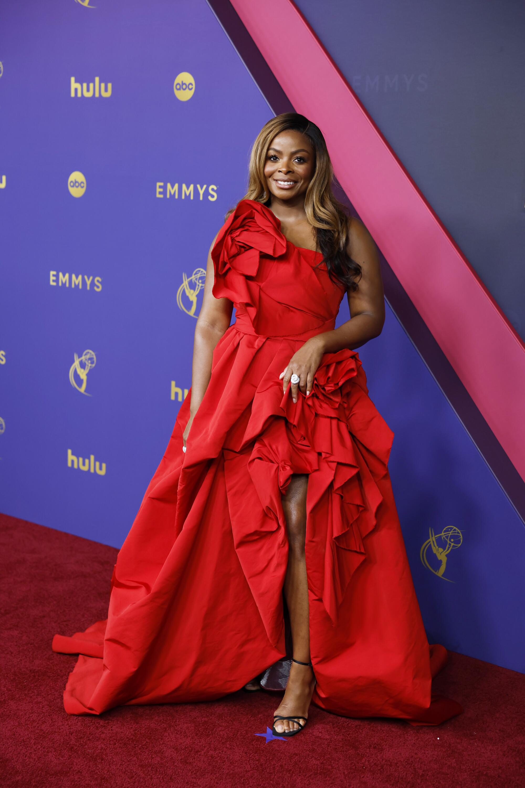 Janelle James wears a red gown with a slit.