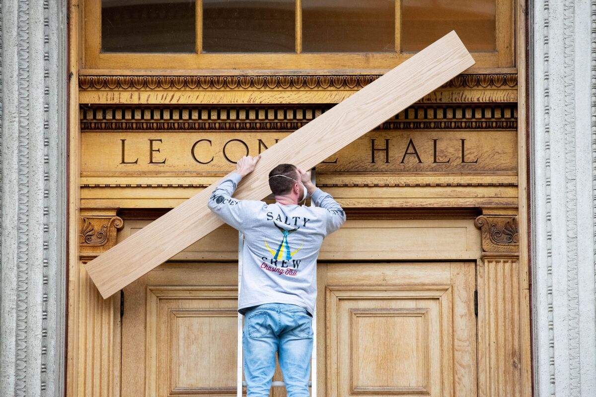 A worker lifts up a plank of oak to cover the name of an academic hall above its doors