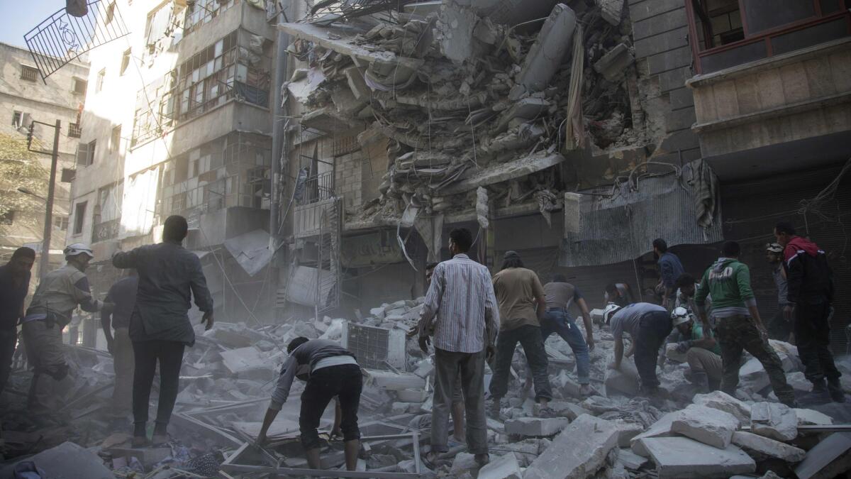 Syrian civilians and rescuers gather at the site of an airstrike by government forces in the rebel-held neighborhood of Shaar in Aleppo on Sept. 27, 2016.