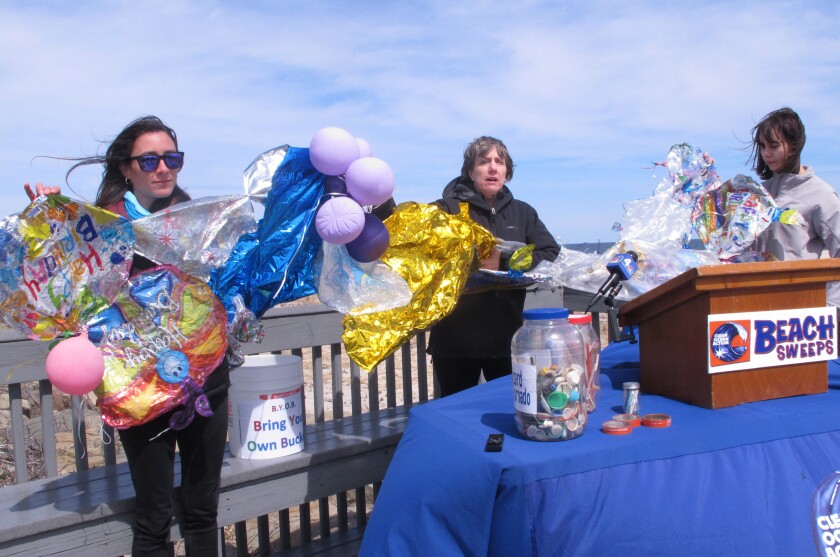 In this April 2, 2019 photo, activists unfurl a banner made of balloons they picked up from the beach at Sandy Hook N.J.  