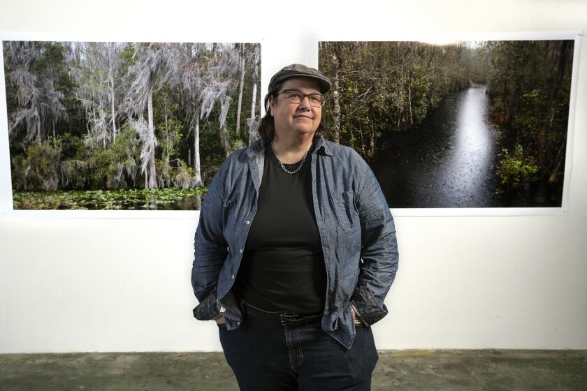 Catherine Opie photographed at her studio in Los Angeles in front of her pictures of swamplands.