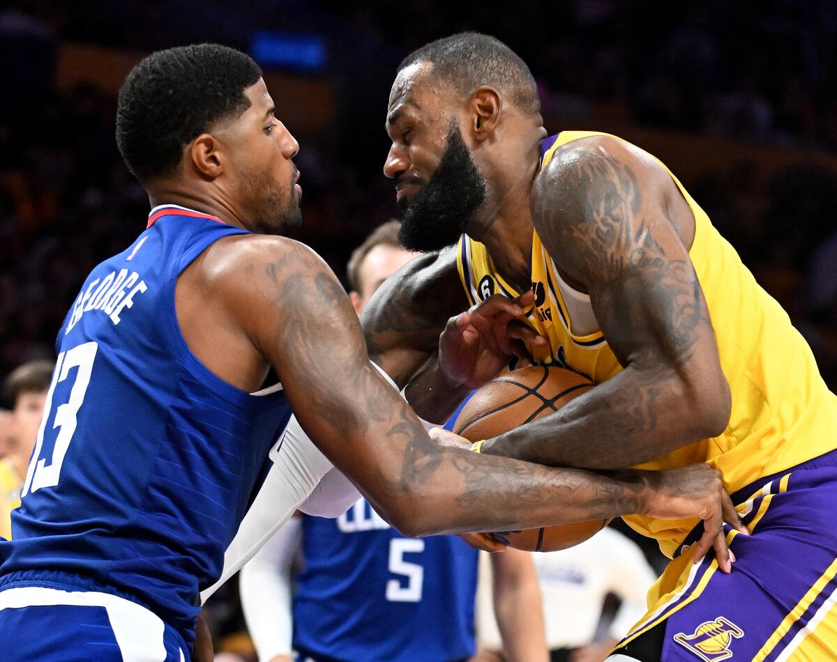 Clippers forward Paul George grabs for the ball against Lakers forward LeBron James on a drive. 