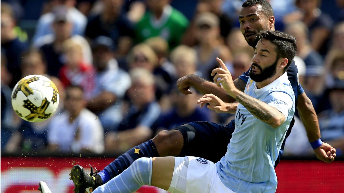 Sporting Kansas City forward Cristian Lobato plays the ball against Galaxy defender Ashley Cole, back, during a match Sept. 24, 2017.
