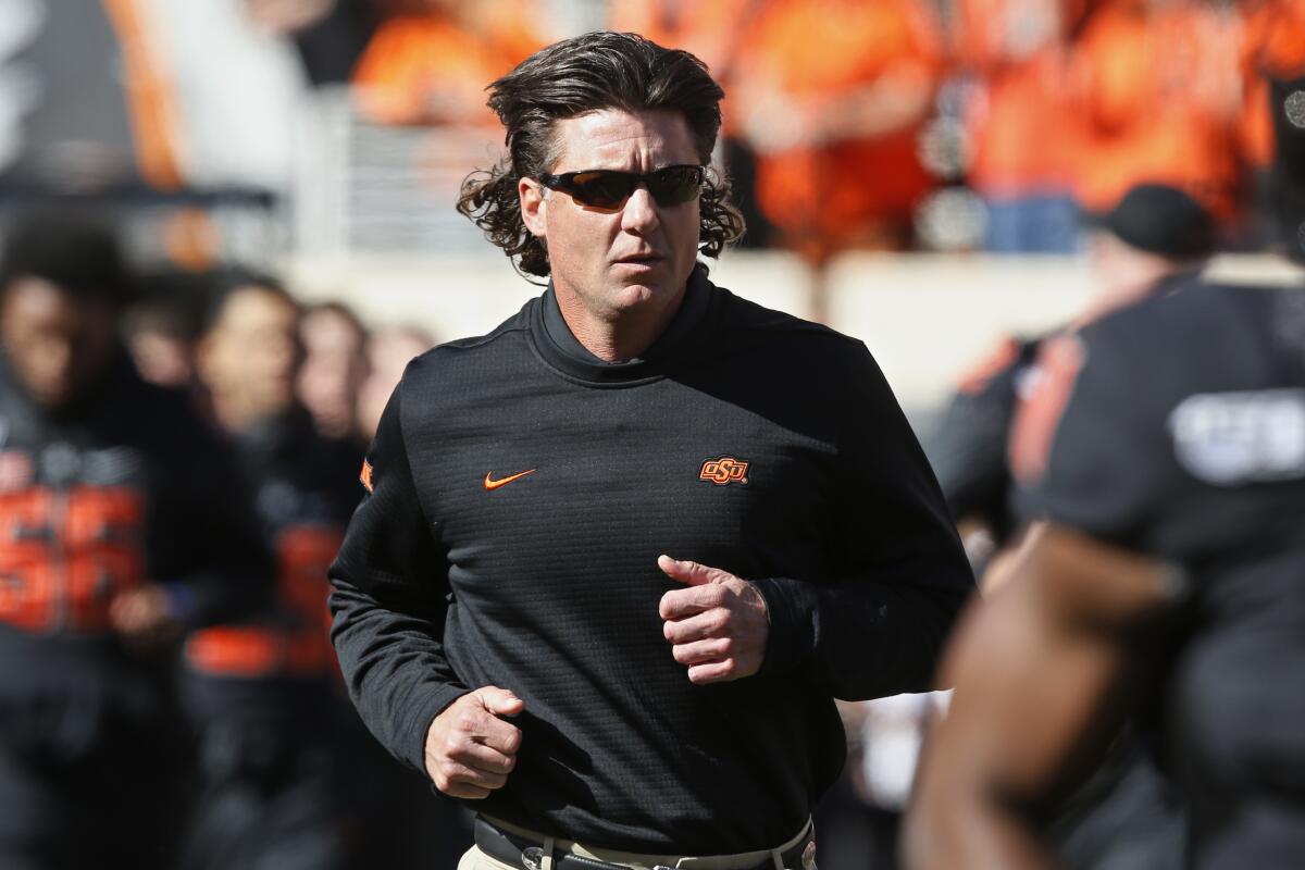 Oklahoma State head coach Mike Gundy runs onto the field.