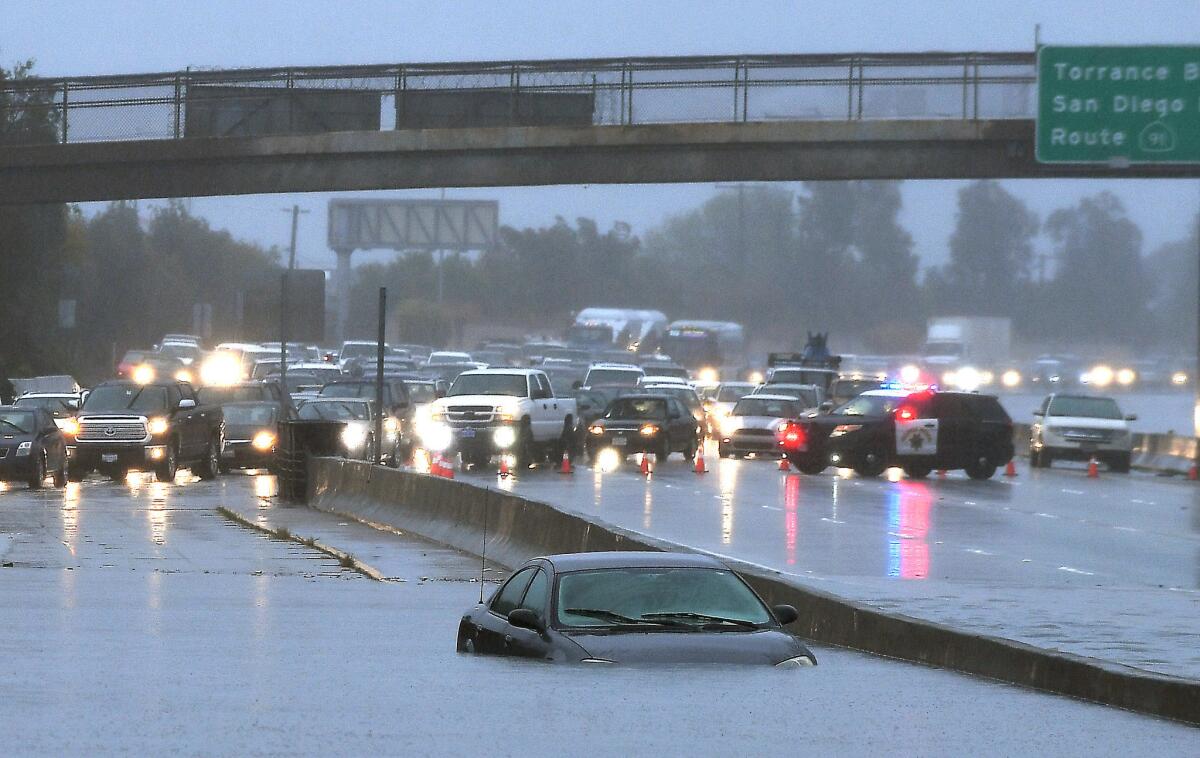 A car is stuck in standing water on the southbound 110 Freeway. All lanes were closed from Carson Street to 223rd Street on Sunday because of flooding.
