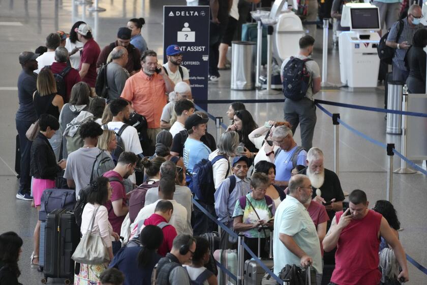 FILE - Passengers wait in line for assistance at the Delta Terminal, July 19, 2024, at Logan International Airport in Boston. Delta CEO Ed Bastian says the airline is facing $500 million in costs for the global technology breakdown that happened earlier this month. (AP Photo/Michael Dwyer, File)