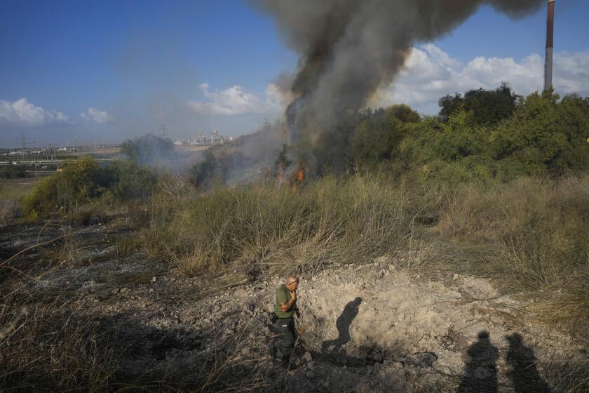 A police officer inspects the area around a fire after the military said it fired interceptors at a missile launched from Yemen that landed in central Israel on Sunday, Sept. 15, 2024. (AP Photo/Ohad Zwigenberg)