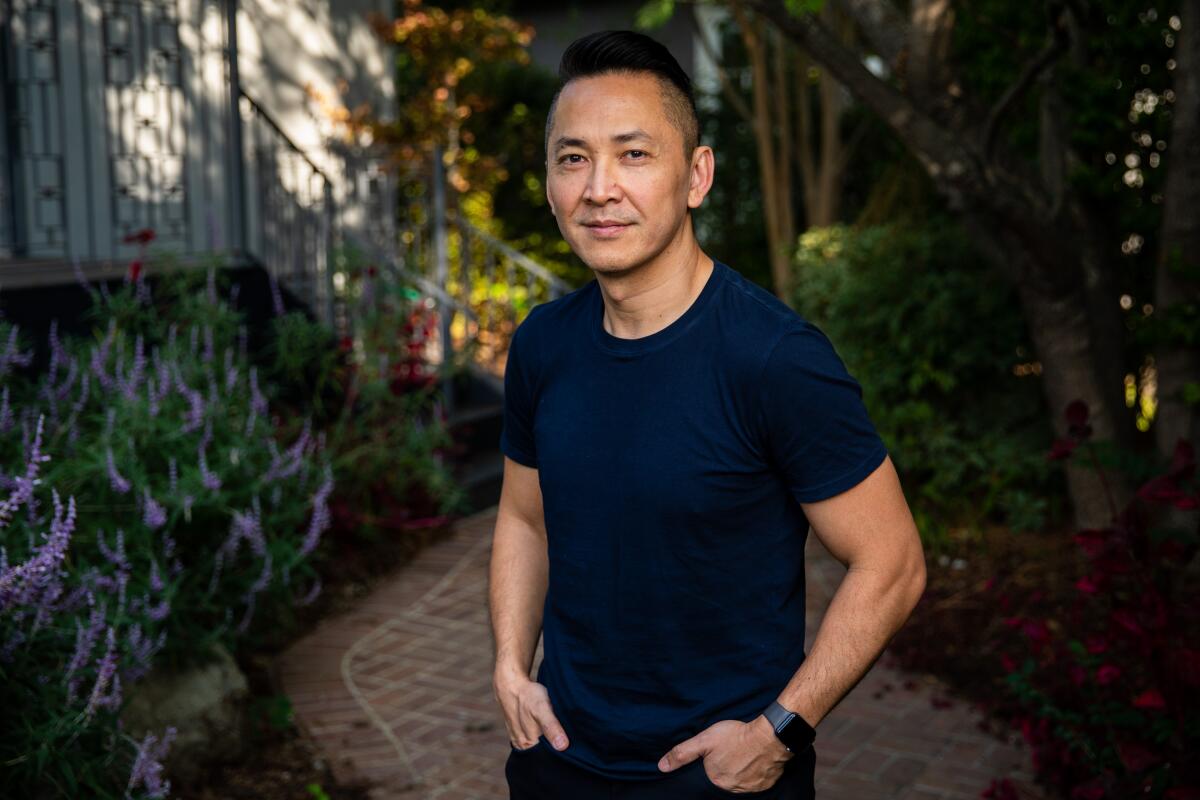 Viet Thanh Nguyen stands on a brick path surrounded by plants.