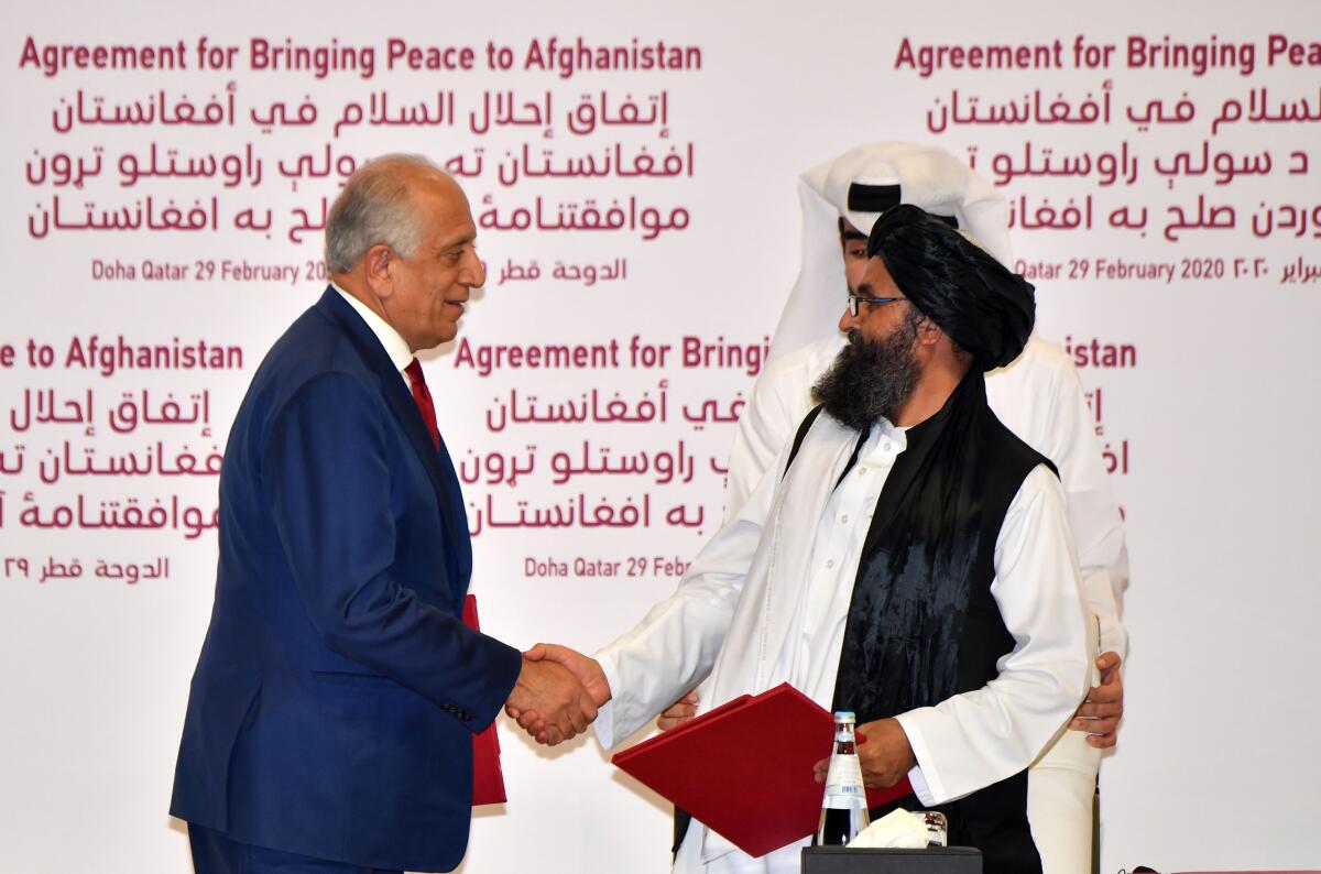 U.S. Special Representative Zalmay Khalilzad, left, and Taliban official Mullah Abdul Ghani Baradar shake hands after signing a peace agreement in Doha, Qatar's capital, on Feb. 29, 2020.