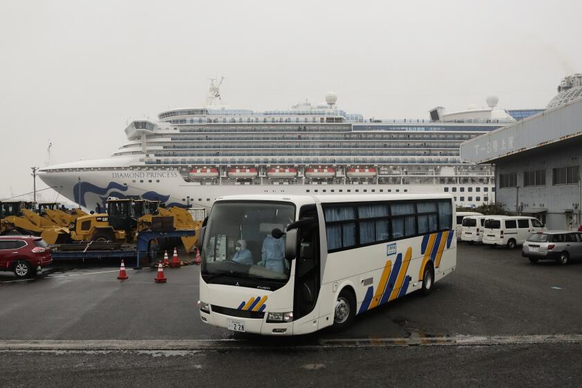A bus leaves the quarantined Diamond Princess cruise ship at a port Sunday, Feb. 16, 2020, in Yokohama, near Tokyo. The U.S. says Americans aboard a quarantined ship will be flown back home on a chartered flight Sunday, but that they will face another two-week quarantine. (AP Photo/Jae C. Hong)