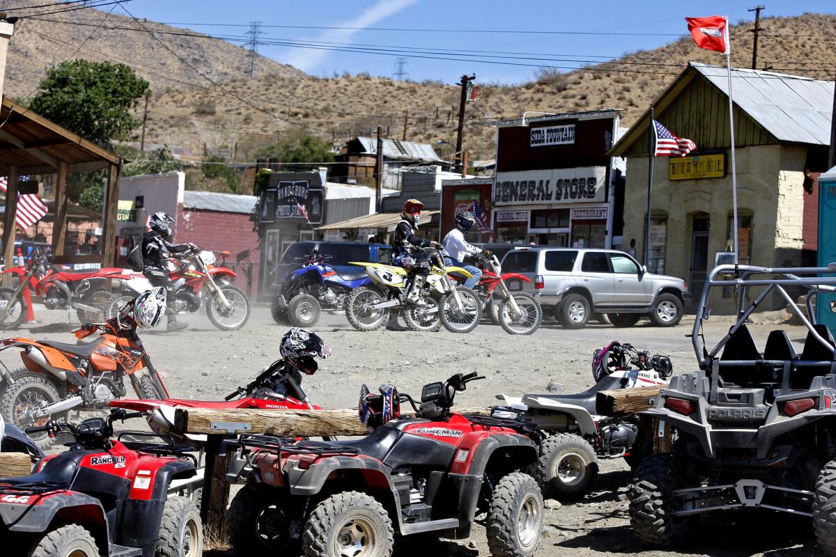 Off-road vehicles line an area in Randsburg, Calif., while riders, in background, prepare to go for a ride in May 2013 after a lunch break. By midmorning on Saturdays, Randsburg's main drag is crowded with off-roaders coming into town for refreshments.