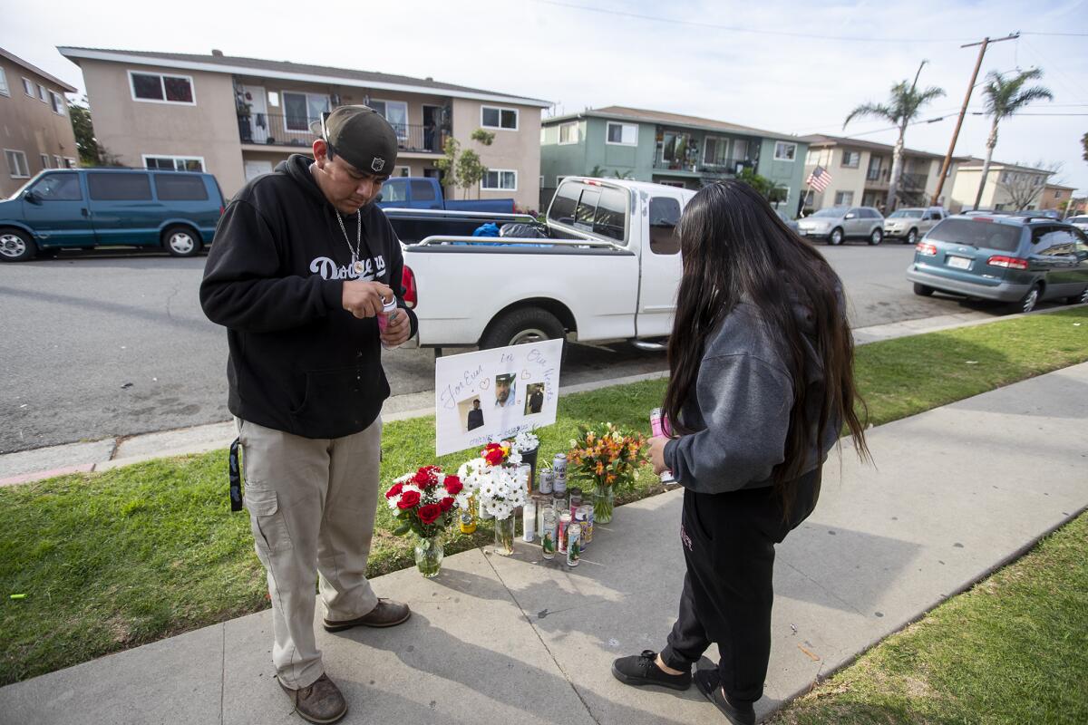 Two neighbors light candles for a 32-year-old man who was shot and killed in the street in Huntington Beach.