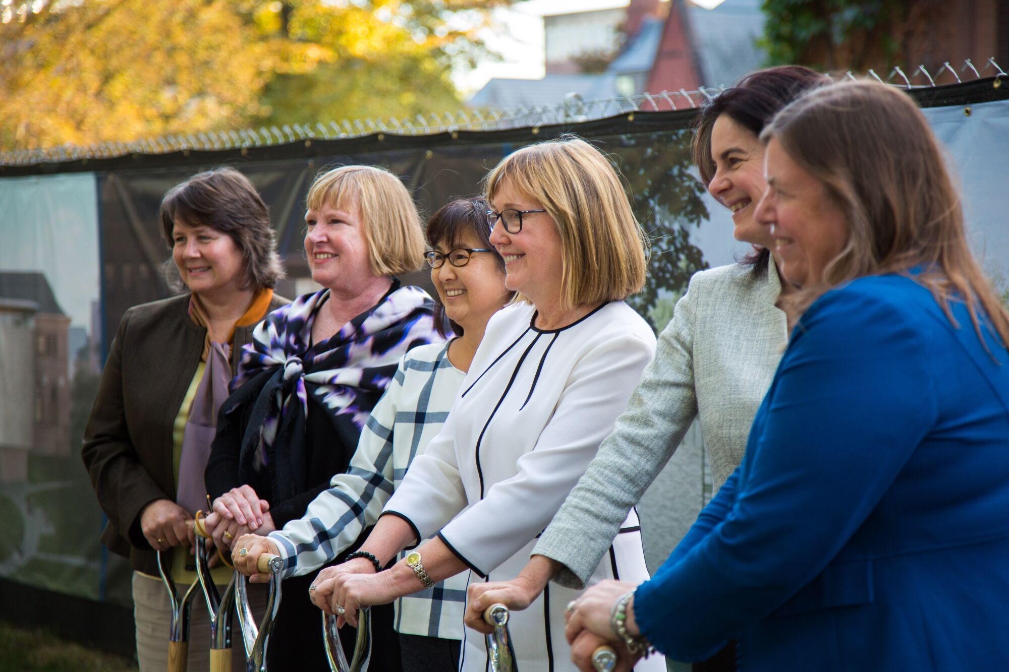 A row of women — with Maya Lin and Smith College president Kathleen McCartney at the center — stand holding shovels.