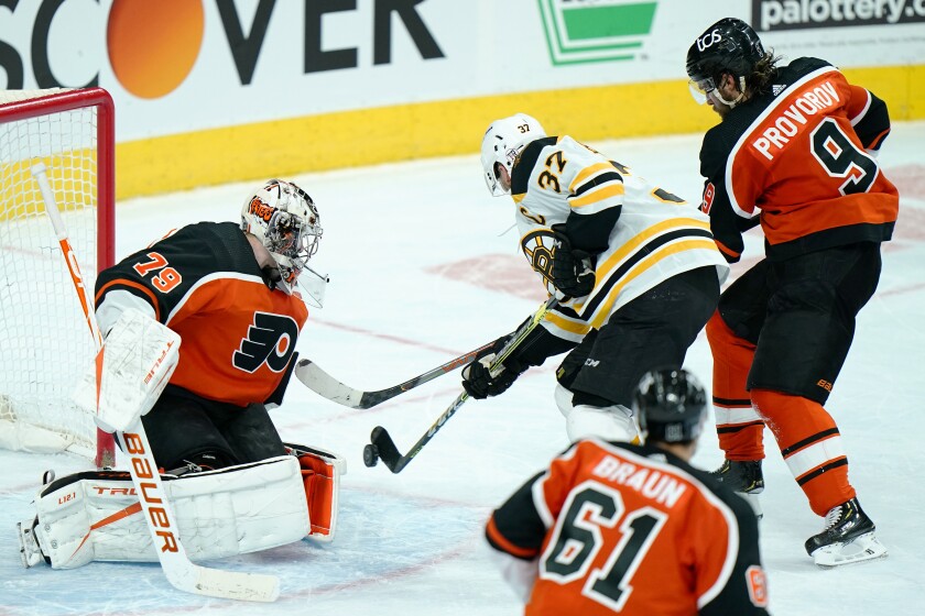 Boston Bruins' Patrice Bergeron (37) scores the game-winning goal past Philadelphia Flyers' Carter Hart (79) during overtime in an NHL hockey game, Wednesday, Feb. 3, 2021, in Philadelphia. (AP Photo/Matt Slocum)
