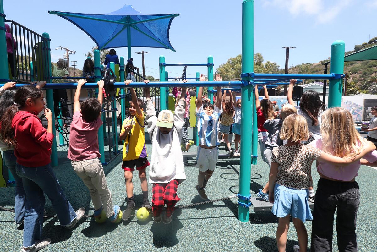 Kids from the Boys & Girls Club jump on the bars at the new Dream Play Yard in Laguna Beach on Friday.