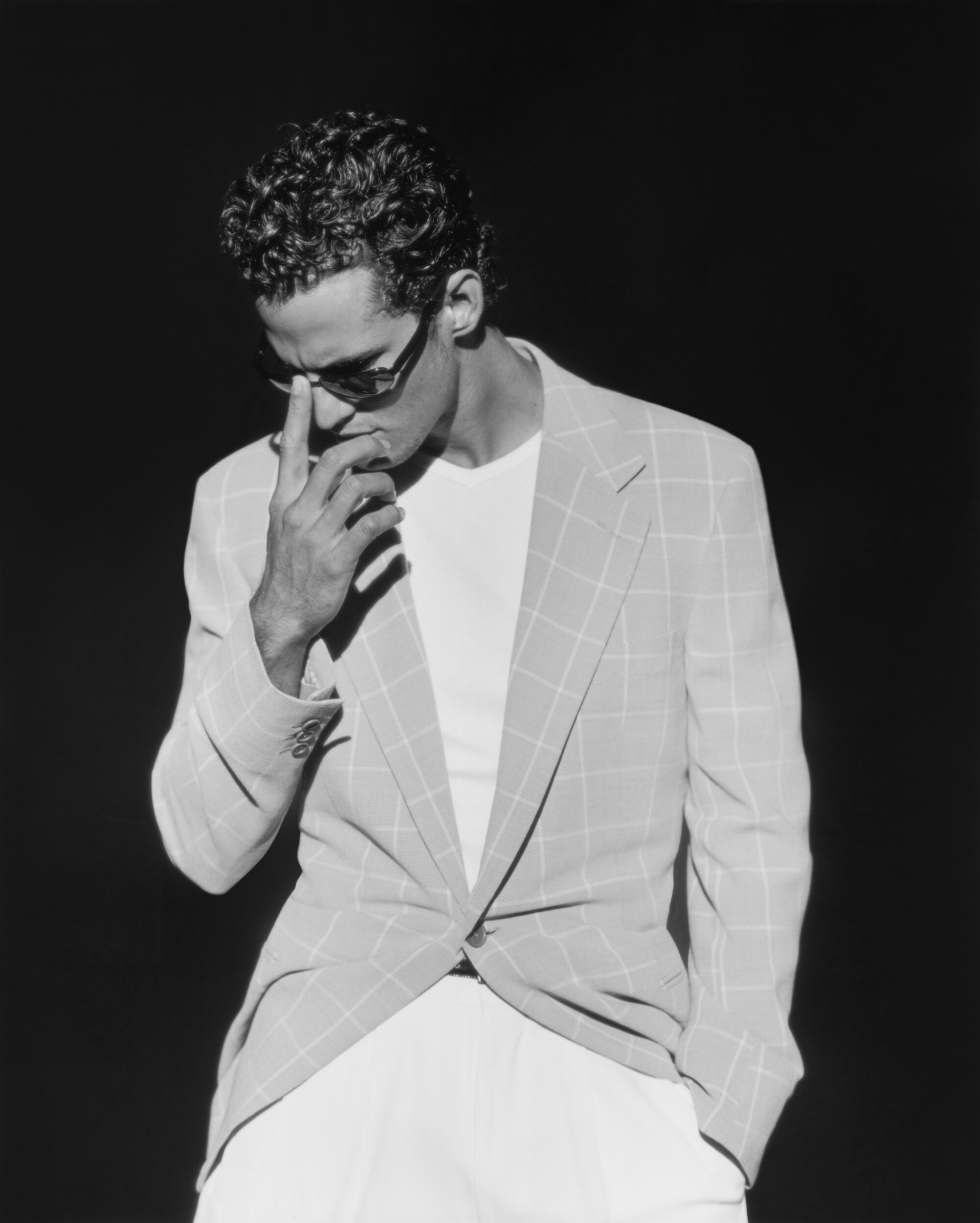 A black-and-white photo of a man in a windowpane-pattern suit jacket