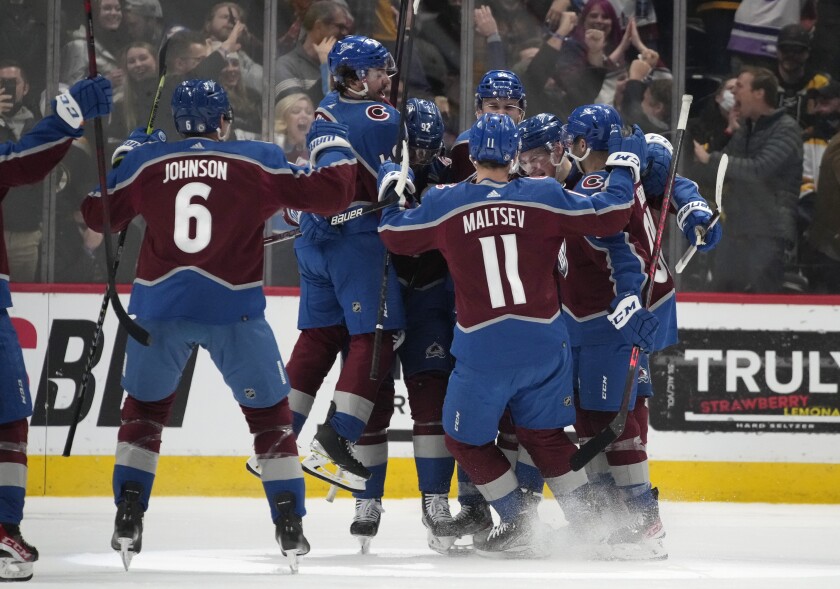 Colorado Avalanche players celebrate with defenseman Cale Makar after his power-play goal in overtime of an NHL hockey game against the Boston Bruins Wednesday, Jan. 26, 2022, in Denver. The Avalanche won 4-3. (AP Photo/David Zalubowski)