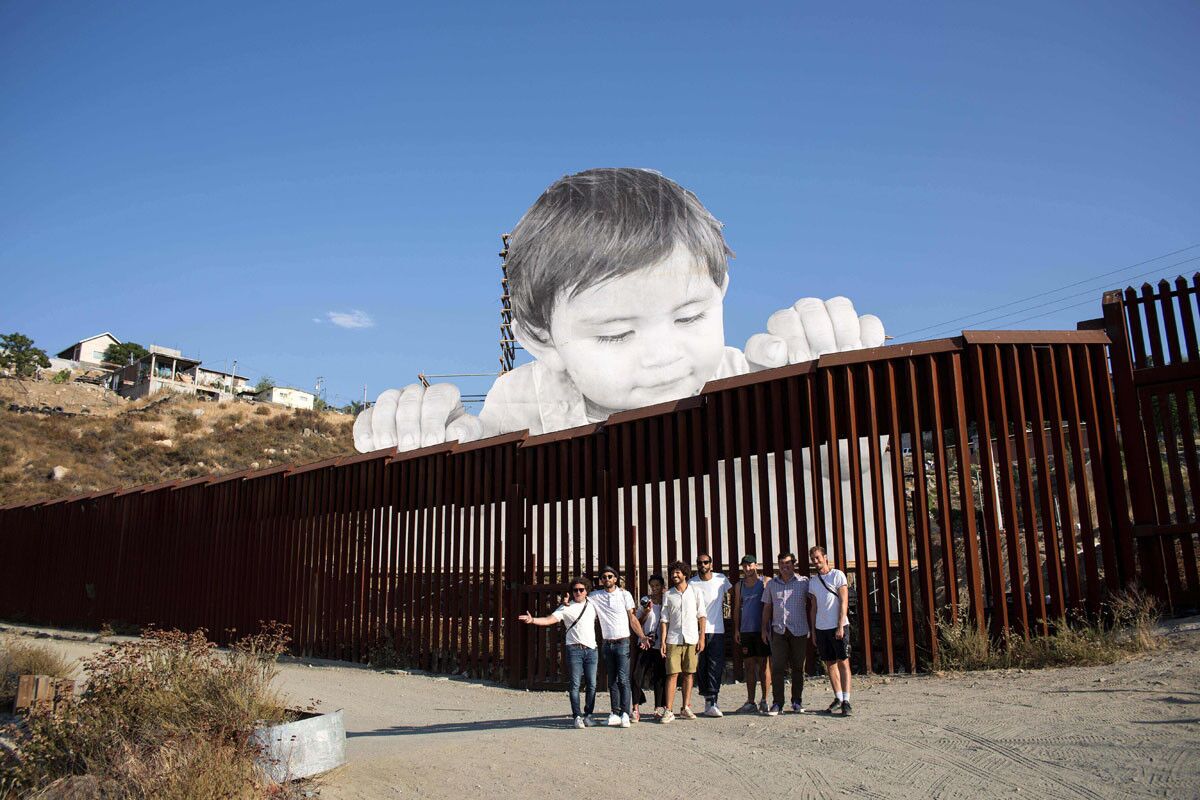French artist JR poses for a group photo near his artwork on the US-Mexico border in Tecate, California. (Getty Images)