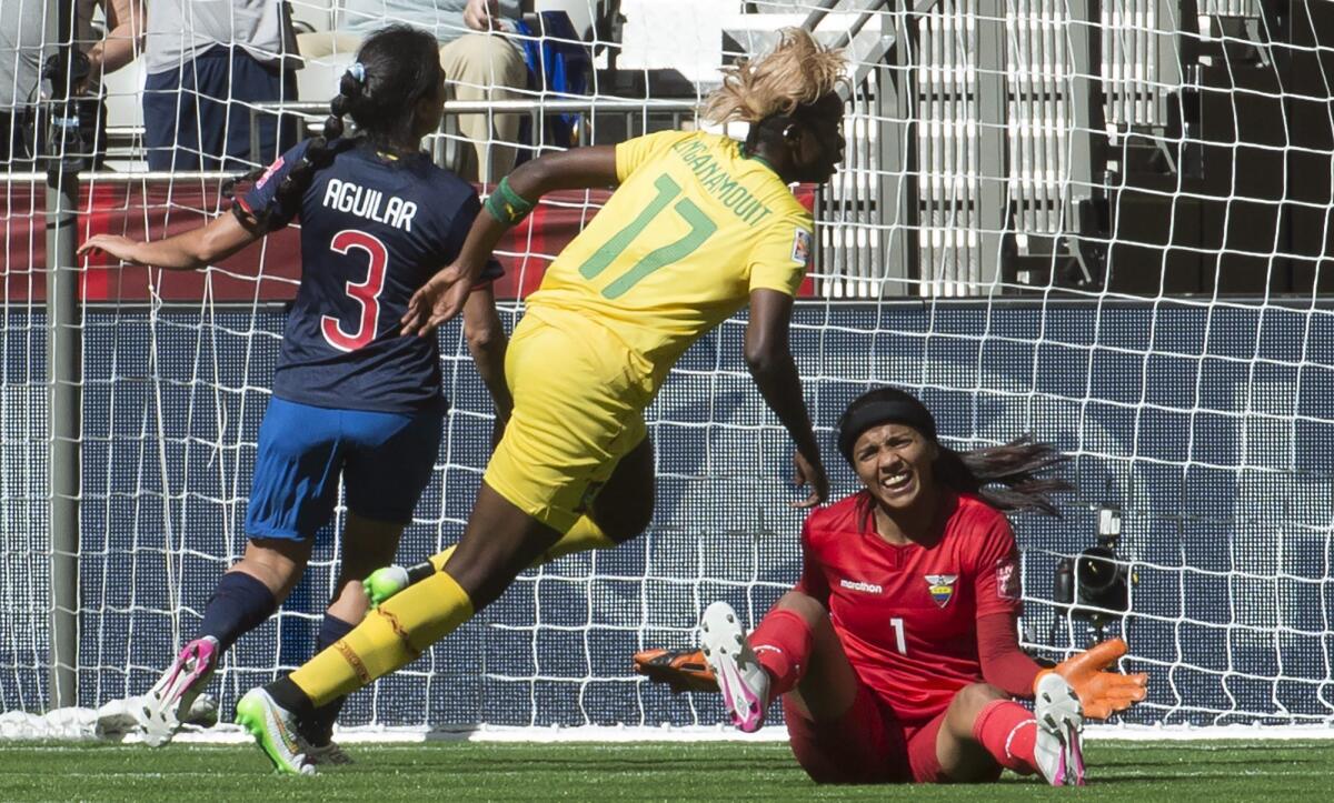 Gaelle Enganamouit, de Camerún, festeja luego de anotar frente a la arquera de Ecuador, Shirley Berruz y a la zaguera Nancy Aguilar, durante un partido de la Copa del Mundo para mujeres.