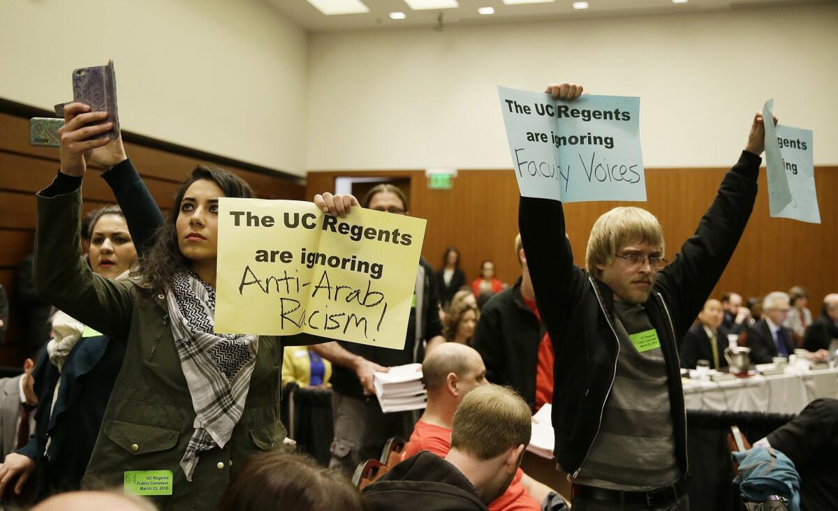 Students hold up protest signs at the end of a public comment period during a University of California Board of Regents meeting Wednesday, March 23, 2016, in San Francisco. A committee of the University of California's governing board unanimously approved a statement Wednesday that cites anti-Semitism as a form of intolerance that campus leaders have a duty to challenge. The committee of the university's Board of Regents voted to send what is being called a "Statement of Principles Against Intolerance" on to the full board for final consideration on Thursday. (AP Photo/Eric Risberg)