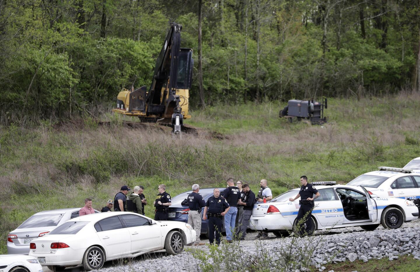Police gather on a road next to construction equipment in a wooded area near where Waffle House shooting suspect Travis Reinking was captured on April 23, 2018, in Nashville, Tenn.