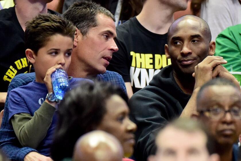 Rob Pelinka talks with Kobe Bryant during an NCAA men's basketball tournament game at Honda Center on March 26, 2016.