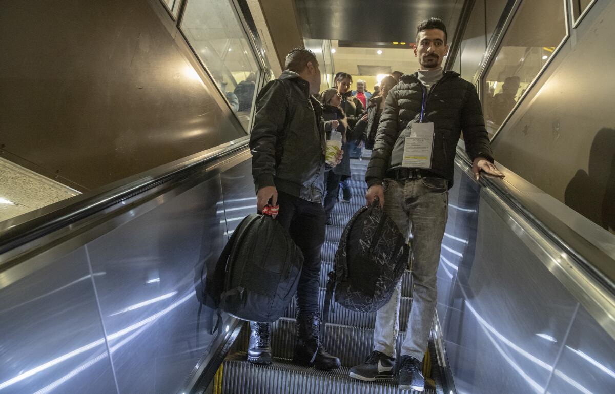 Sirvan Moradi, right, descends an escalator at the Seattle airport.