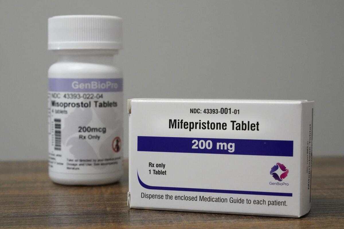 Containers of the medications mifepristone and misoprostol sit on a table.