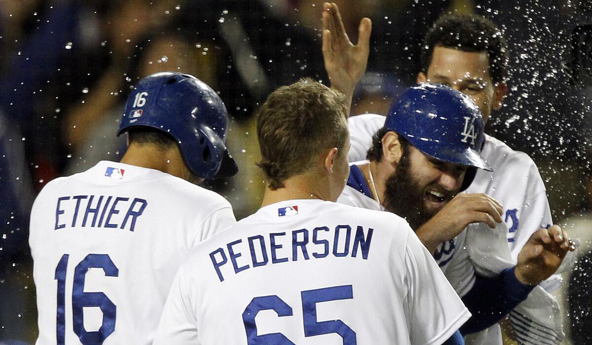 Dodgers' Scott Van Slyke, right, is mobbed in celebration by Andre Ethier (16), Joc Pederson (65) and Carlos Frias after scoring on a wild pitch in the 12th inning Saturday to give the Dodgers a 6-5 win over the Colorado Rockies.