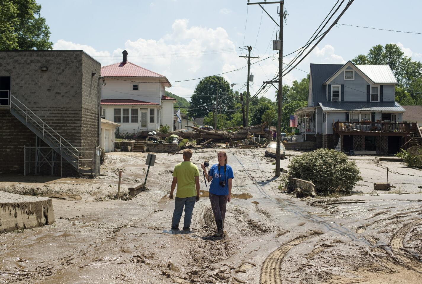 People stand in the middle of a mud-covered street in Clendenin, W. Va., after the Elk River flooded.