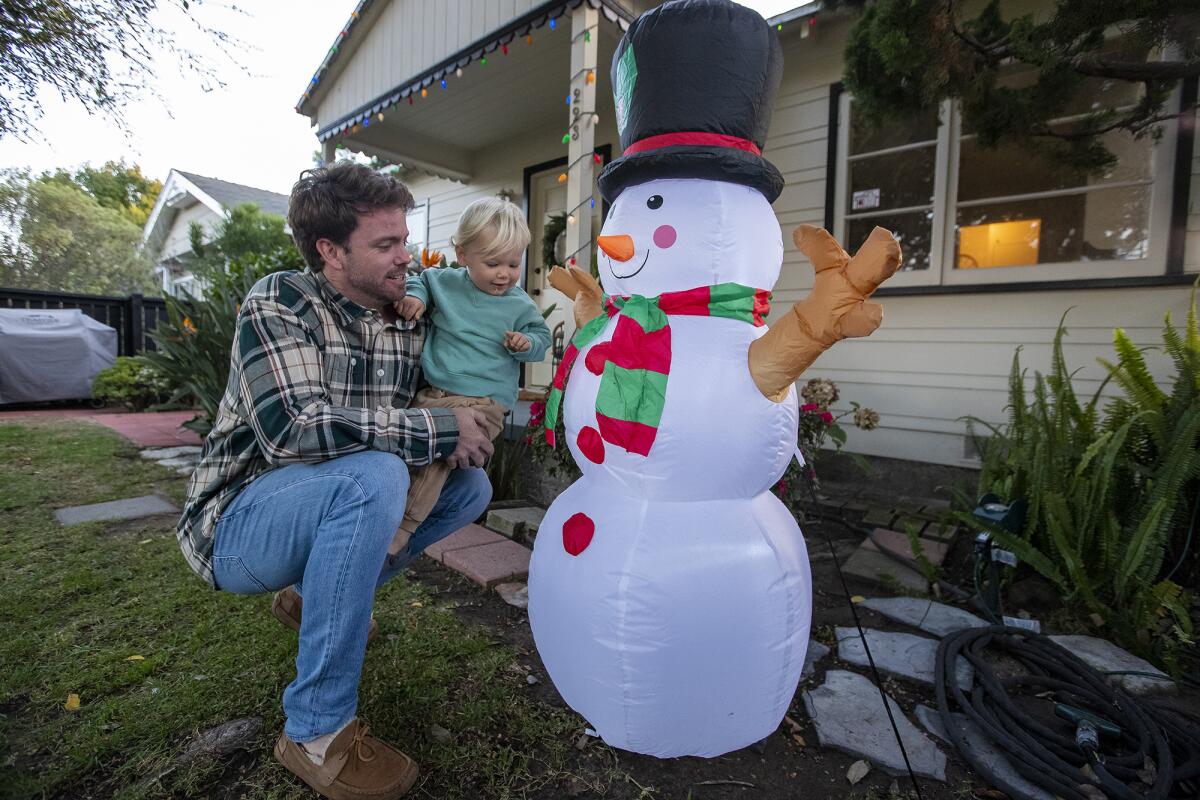 Bobby Talley, and his son, Jude, with an inflatable Frosty the Snowman at their house in Costa Mesa on Friday, Dec. 3.