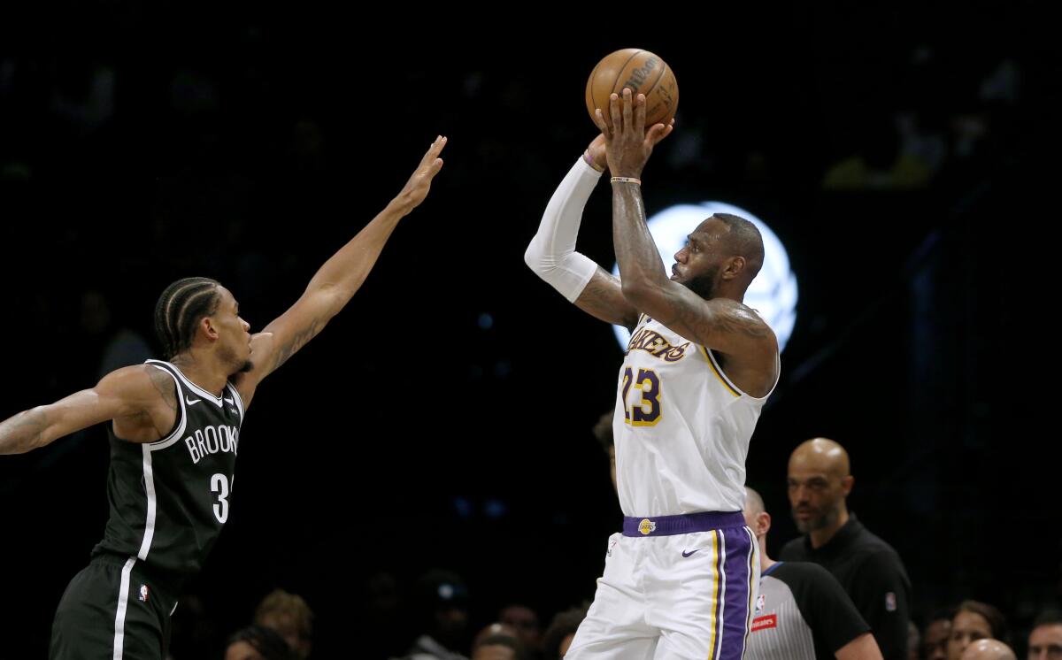 Lakers forward LeBron James makes a 3-point basket over Brooklyn Nets center Nic Claxton Sunday in New York. 