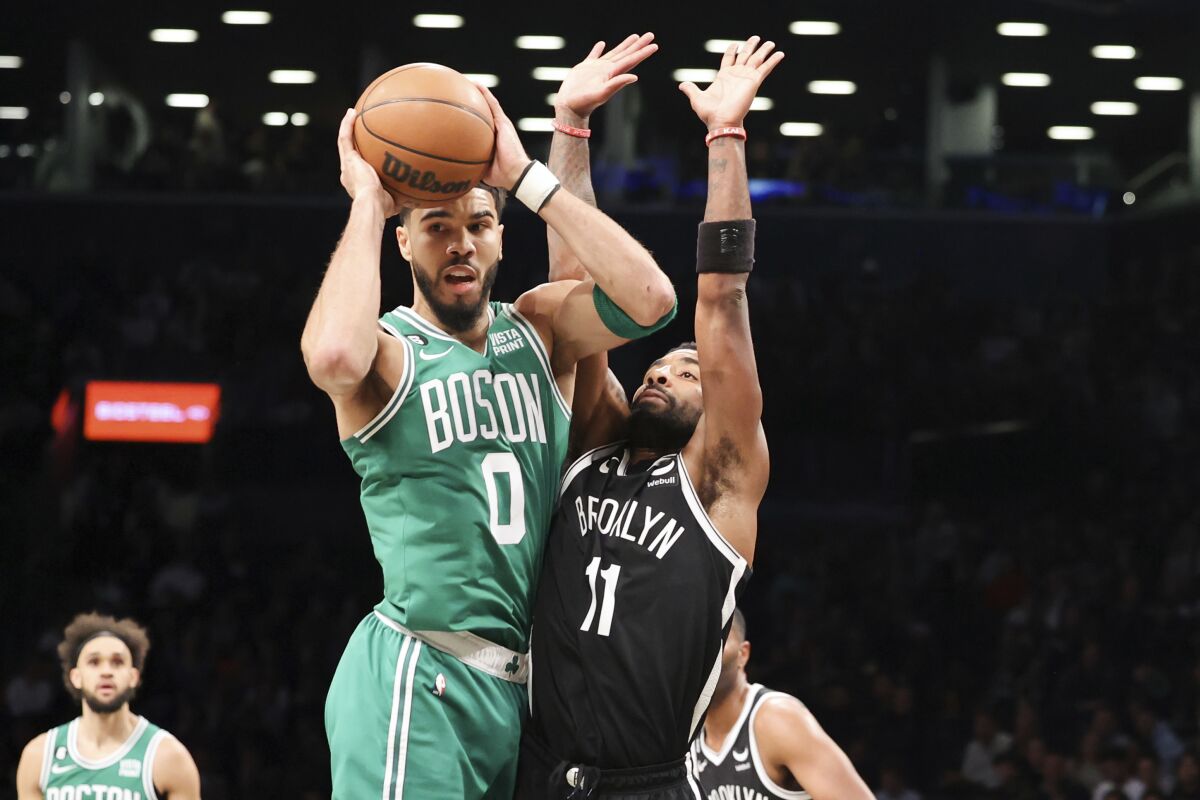 Boston Celtics forward Jayson Tatum (0) looks to pass the ball against Brooklyn Nets guard Kyrie Irving (11) during the first half of an NBA basketball game, Sunday, Dec. 4, 2022, in New York. (AP Photo/Jessie Alcheh)