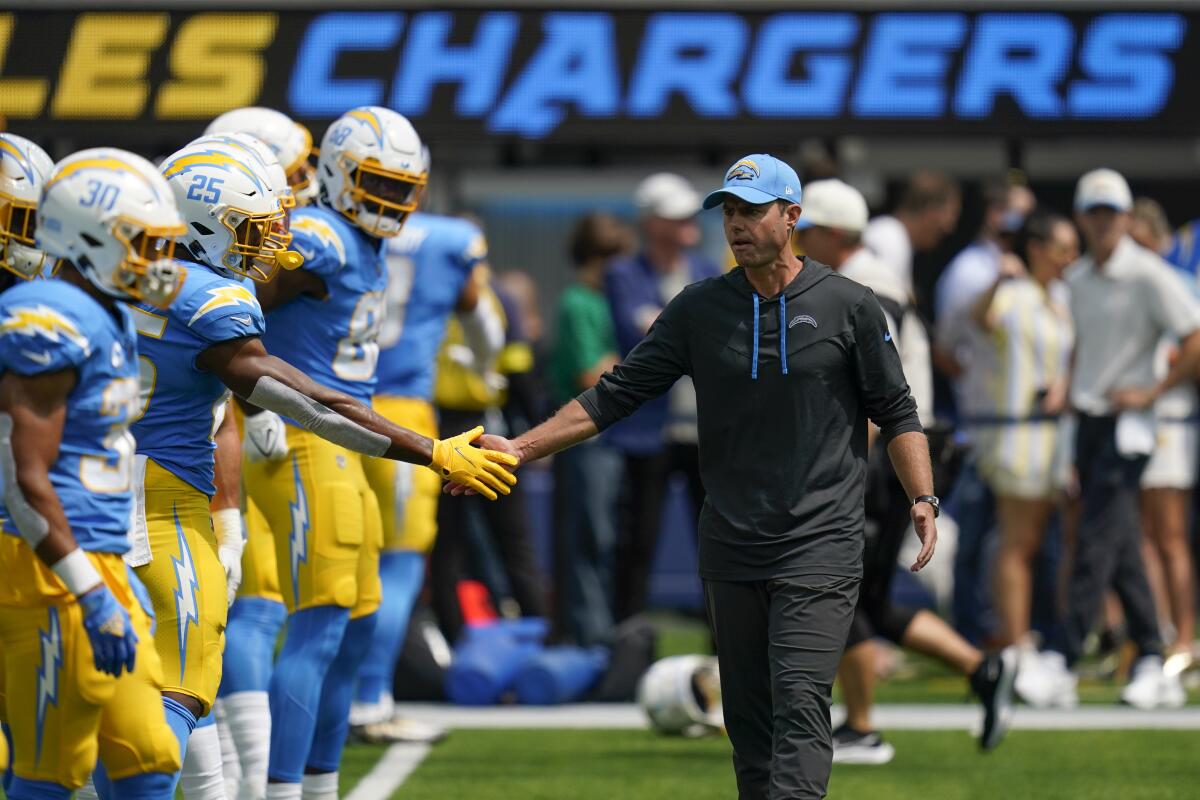 Chargers head coach Brandon Staley greets his players on the sideline.