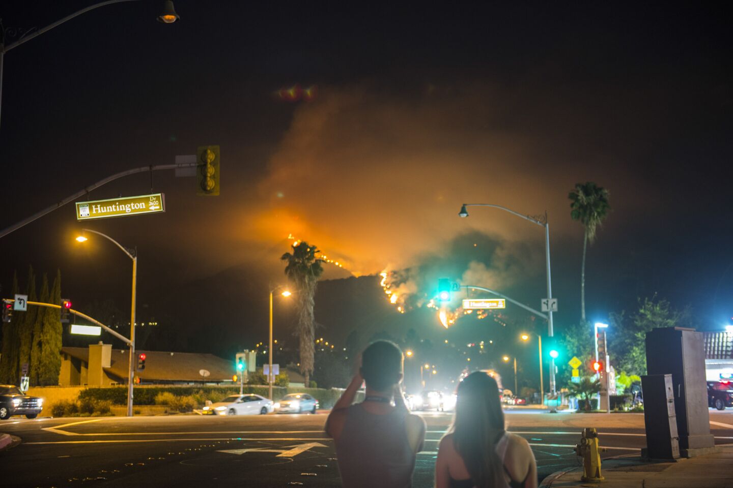 Onlookers take pictures of the Fish fire Monday evening off Huntington Drive as the fire burns uphill.