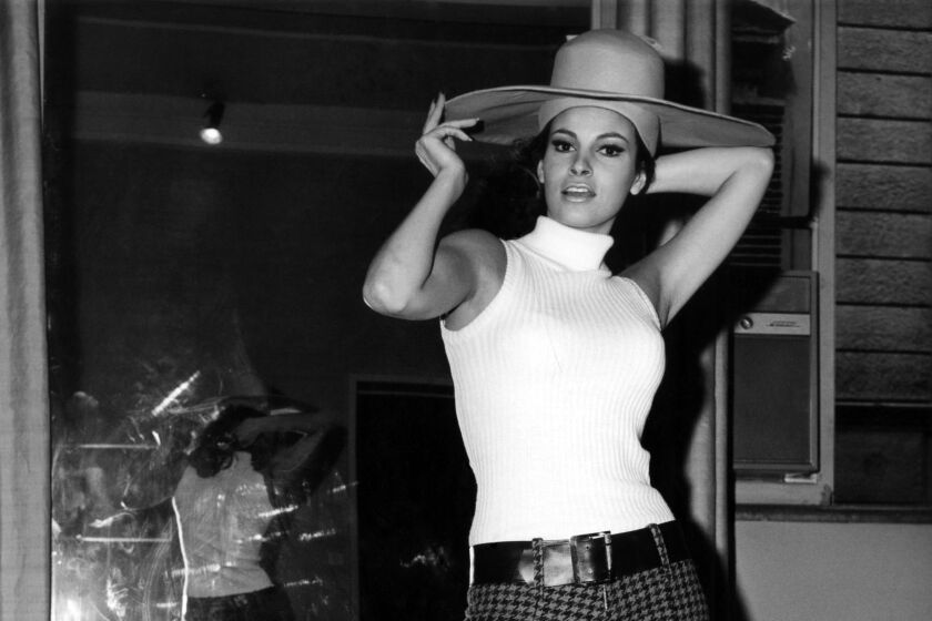 Woman, Raquel Welch wearing a wide brimmed hat and white tank top turtle neck, plaid pants and boots in black and white photo